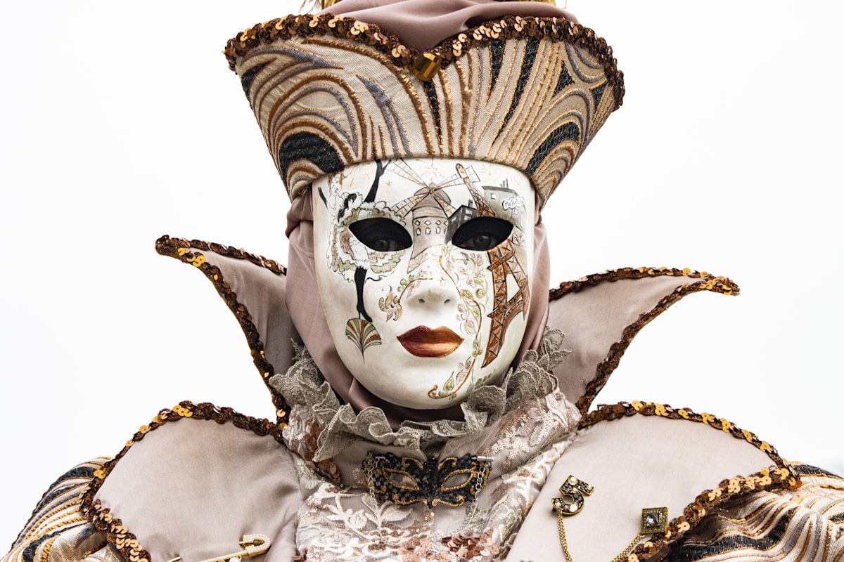 Ornate Venetian carnival mask in gold and white displayed against a dark background